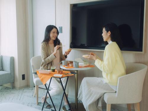 two women sitting at a table eating food at HOTEL THE LEBEN OSAKA in Osaka