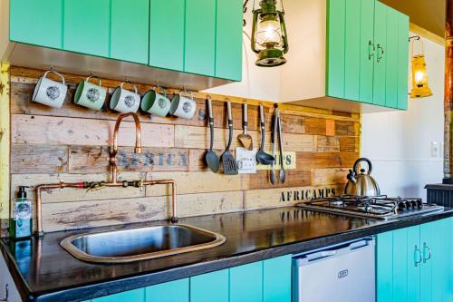 a kitchen with green cabinets and a sink at AfriCamps Addo in Swanepoelskraal