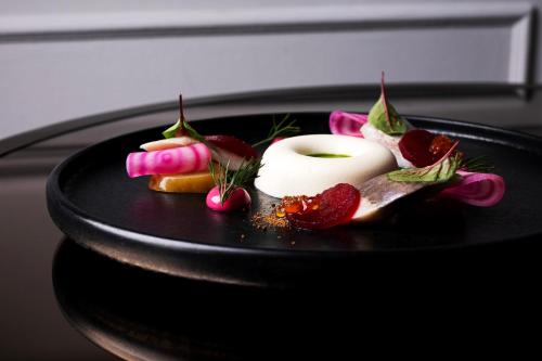 a black plate with some food on a table at Hotel Bristol, A Luxury Collection Hotel, Warsaw in Warsaw