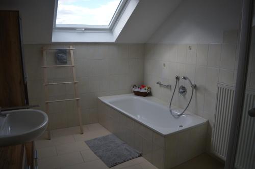 baño con bañera, lavabo y ventana en Ferienwohnung Rißblick 