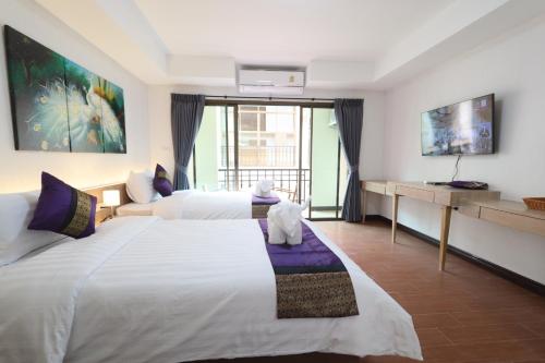 a hotel room with two beds and a desk at Peacock De Pai Hotel in Pai