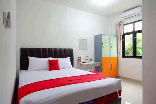 a bedroom with a large bed with a red blanket at RedDoorz Syariah near Universitas Jenderal Soedirman 2 in Purwokerto