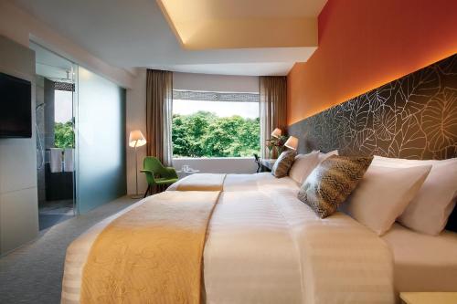 ein Schlafzimmer mit einem großen Bett und einer orangefarbenen Wand in der Unterkunft D'Hotel Singapore managed by The Ascott Limited in Singapur