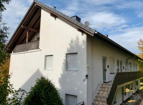 Cette maison blanche dispose d'un balcon et d'un escalier. dans l'établissement Appartement Aussen PFUI - Innen HUI, à Willingen