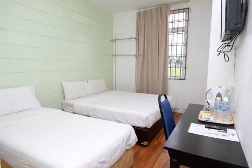 een kamer met 2 bedden, een tafel en een televisie bij Ridel Boutique Hotel in Wakaf Che Yeh