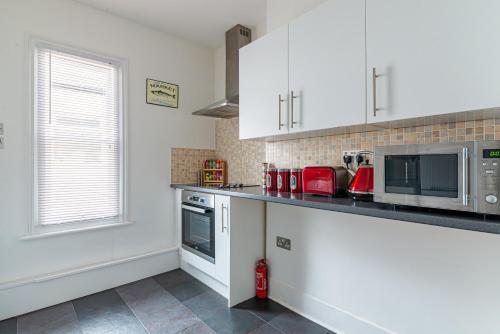 a kitchen with white cabinets and a microwave at Woodgrange in Southend-on-Sea