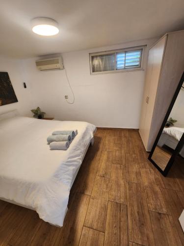 a bedroom with a white bed and a wooden floor at Beit Nofesh in Tiberias