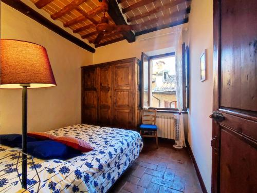 een slaapkamer met een bed, een lamp en een raam bij Convento San Gimignano Apartments in San Gimignano