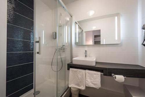 bagno con doccia, lavandino e specchio di Logis hôtel restaurant la Haute Forêt a Vertou