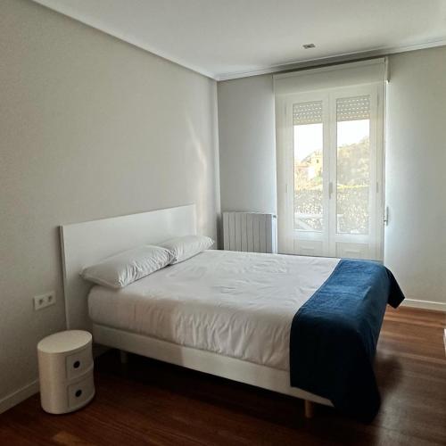 a bedroom with a white bed and a window at CASA AZUL SANTA KATALINA in Mundaka