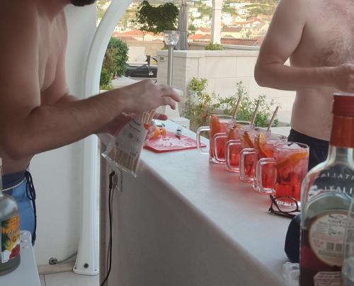a shirtless man standing at a counter with a row of drinks at Apartment Making memories in Pučišća