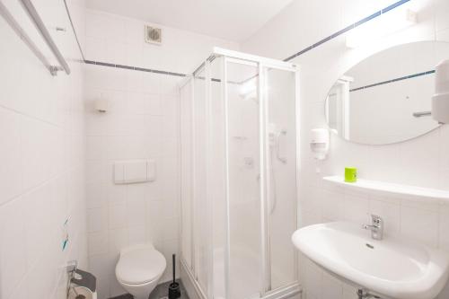 a white bathroom with a shower and a sink at Hotel garni Zwickau-Mosel in Mülsen