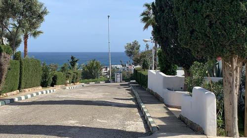 a road with a white fence and trees and the ocean at Villa Jasmin 15 in M'diq