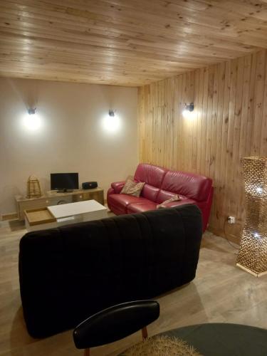 a living room with a red couch and a table at Gîte l'Enclos Ô rendez-vous Roquefeuil-Pays de sault- avec jardin in Roquefeuil