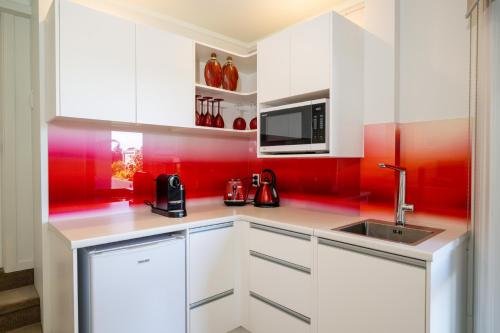 a kitchen with white cabinets and red walls at Absolute Beach in Mount Maunganui