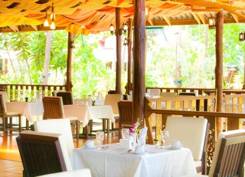 ein Restaurant mit weißen Tischen, Stühlen und einem Sonnenschirm in der Unterkunft Sayang Beach Resort Koh Lanta in Ko Lanta