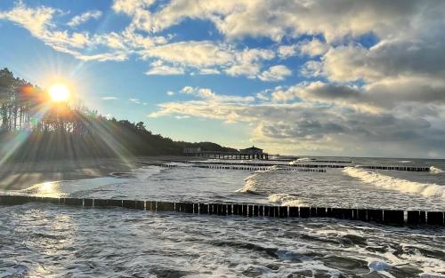 a view of the ocean with the sun in the sky at Interferie Cechsztyn in Ustronie Morskie