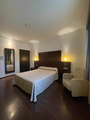 a bedroom with a large bed and a chair at Complejo Leo 24H in Monesterio