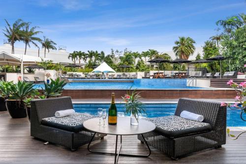 eine Terrasse mit einem Tisch und Stühlen sowie einer Flasche Wein in der Unterkunft Shangri-La The Marina, Cairns in Cairns