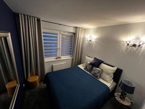 a bedroom with a blue bed and a window at Apartament VIP-2 in Reda