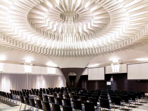 a large room with black chairs and a large ceiling at Pullman Eindhoven Cocagne in Eindhoven