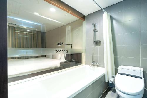 a bathroom with a shower and a toilet and a mirror at Ramada Encore by Wyndham CheonAn in Cheonan