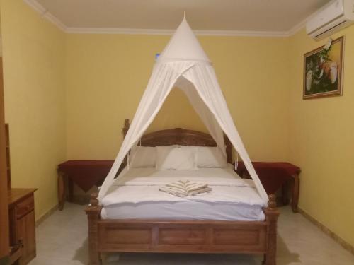 a bed with a canopy in a room at Khailash Warung and Home Stay in Sidemen