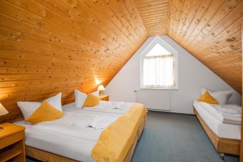 two beds in a room with a wooden ceiling at Hotel garni Zwickau-Mosel in Mülsen