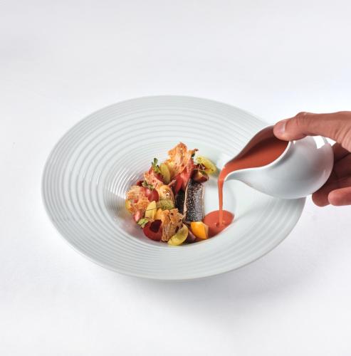 a person holding a white plate of food with a spoon at L'AND Vineyards - Relais & Châteaux in Montemor-o-Novo