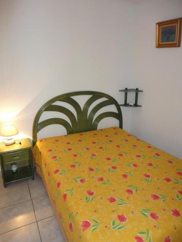 - une chambre avec un lit doté d'un couvre-lit jaune et de fleurs dans l'établissement OREE DU GOLF II Joli T3 piscine proche golf Cap d'Agde, au Cap d'Agde