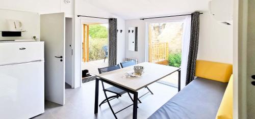 a kitchen and dining room with a table and a refrigerator at Camping Kévano Plage in Pianottoli-Caldarello