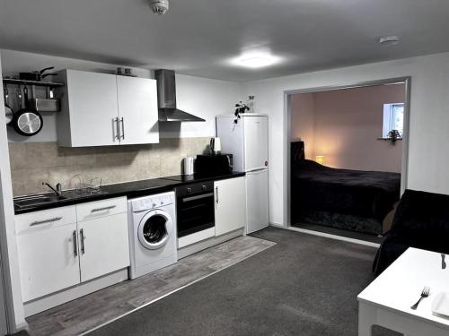 a kitchen with white cabinets and a bed in a room at Studio flat in Sawbridgeworth in Sawbridgeworth