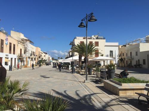 a street with benches and buildings in a city at Le Palme Di Conturrana in San Vito lo Capo