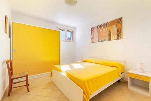 um quarto com uma cama amarela e uma cadeira em Salentoandmore - Villetta Lecci em Salve