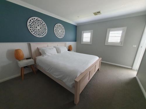 een slaapkamer met een groot bed en 2 ramen bij Located between picturesque Lake Illawarra and Windang beach in Windang