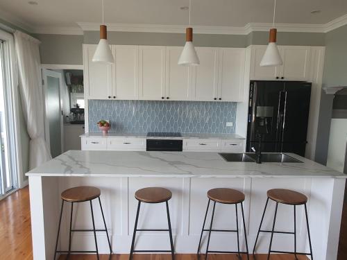 een keuken met een witte bar en 3 barkrukken bij Located between picturesque Lake Illawarra and Windang beach in Windang