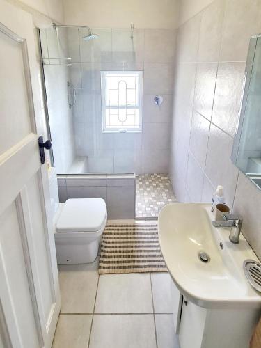 a white bathroom with a toilet and a sink at Dann's Corner in Mossel Bay
