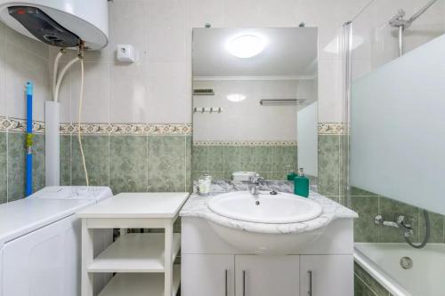 La salle de bains blanche est pourvue d'un lavabo et d'un miroir. dans l'établissement 040 Apartamento Norra, à Torrevieja