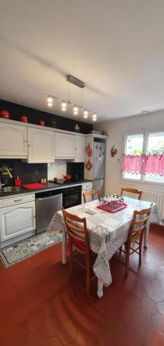 une cuisine avec une table et des chaises et une cuisine avec des armoires blanches dans l'établissement ENTRE Terre ET Mer, à Saint-Aubin-le-Cauf