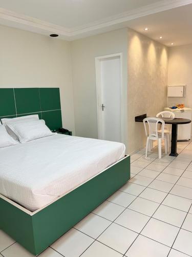 a bedroom with a large bed and a table at Pousada Paraíso in Teresina