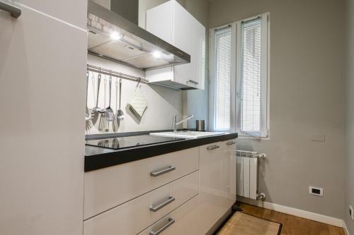 una cucina con armadi bianchi, lavandino e finestra di Maison Marconi a Bologna