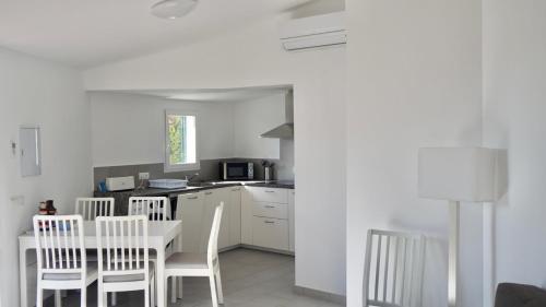 a kitchen with a white table and chairs and a kitchen with a counter at Casa la Marinera in Binibeca