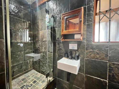 a bathroom with a sink and a shower at Knysna Lodge - Self Catering Unit with Woodfired Hot Tub in Knysna