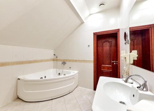un bagno bianco con vasca e lavandino di Hotel Sfinksas a Kaunas