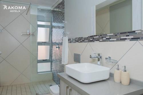 a white bathroom with a sink and a shower at Deluxe 3 Bed Apartment in Polokwane