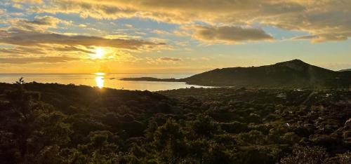 a sunset over a body of water with a mountain at Camping Kévano Plage in Pianottoli-Caldarello