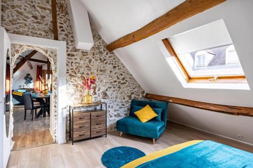 - une chambre mansardée avec une chaise bleue et une table dans l'établissement Le Cobalt - À 10 minutes de Disneyland Paris, à Gouvernes