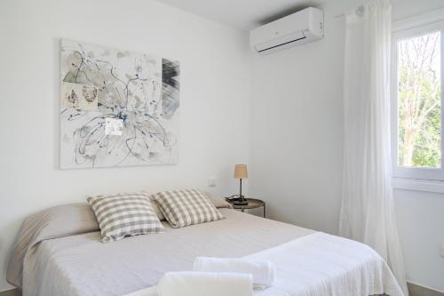 een witte slaapkamer met een bed en een raam bij Cas Buc - Villa con piscina a pasitos del mar in Cala Blanca