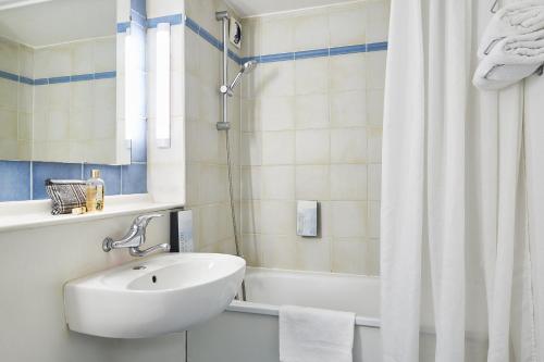 y baño blanco con lavabo y ducha. en Kyriad Direct Soissons en Soissons