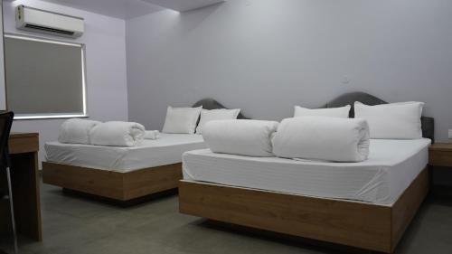 two beds with white pillows in a room at POD N BEYOND SMART HOTEL @BISTUPUR in Jamshedpur